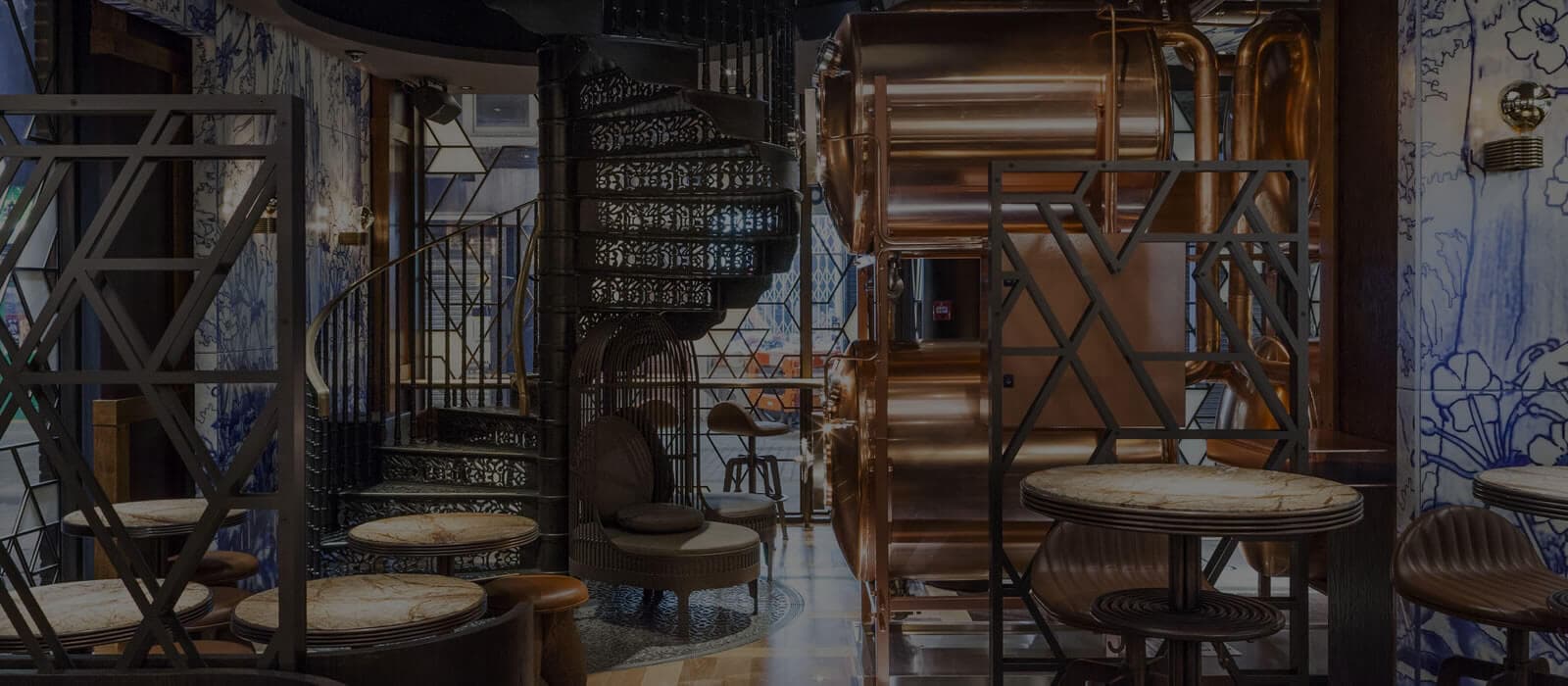 Ornate spiral staircase and copper brewing tanks at The Duck and Rice, London