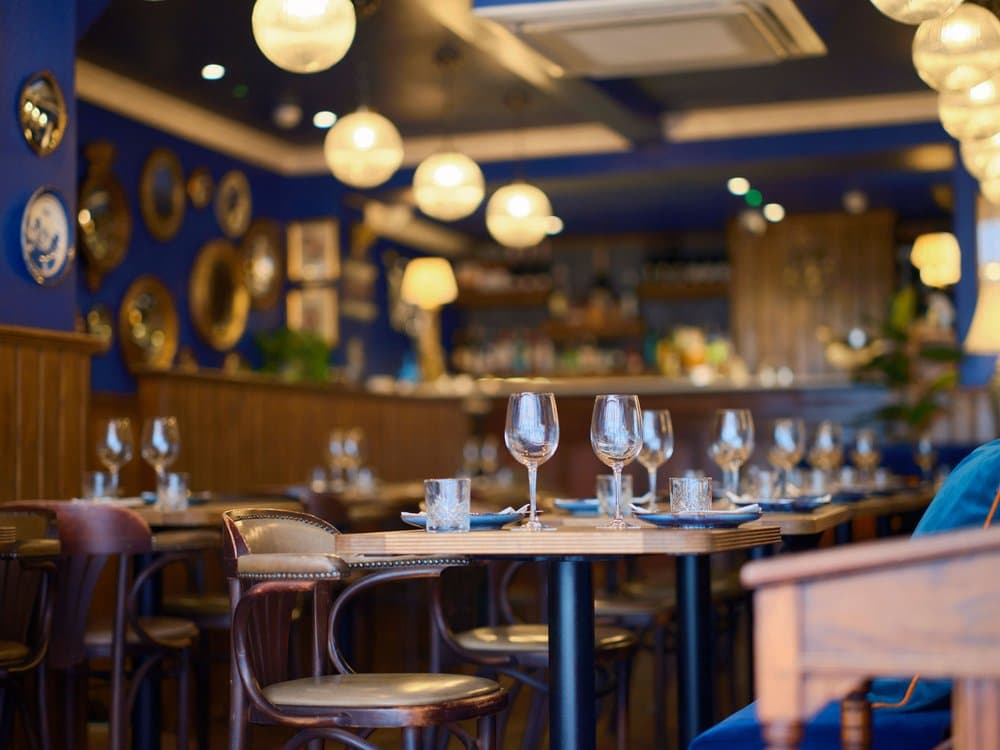 Elegant table setting with wine glasses and decorative blue walls at 27 Old Compton Street, London