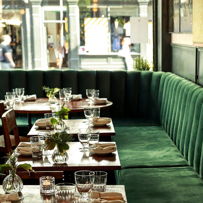 Luxurious green velvet banquette seating area at Cora Pearl, London