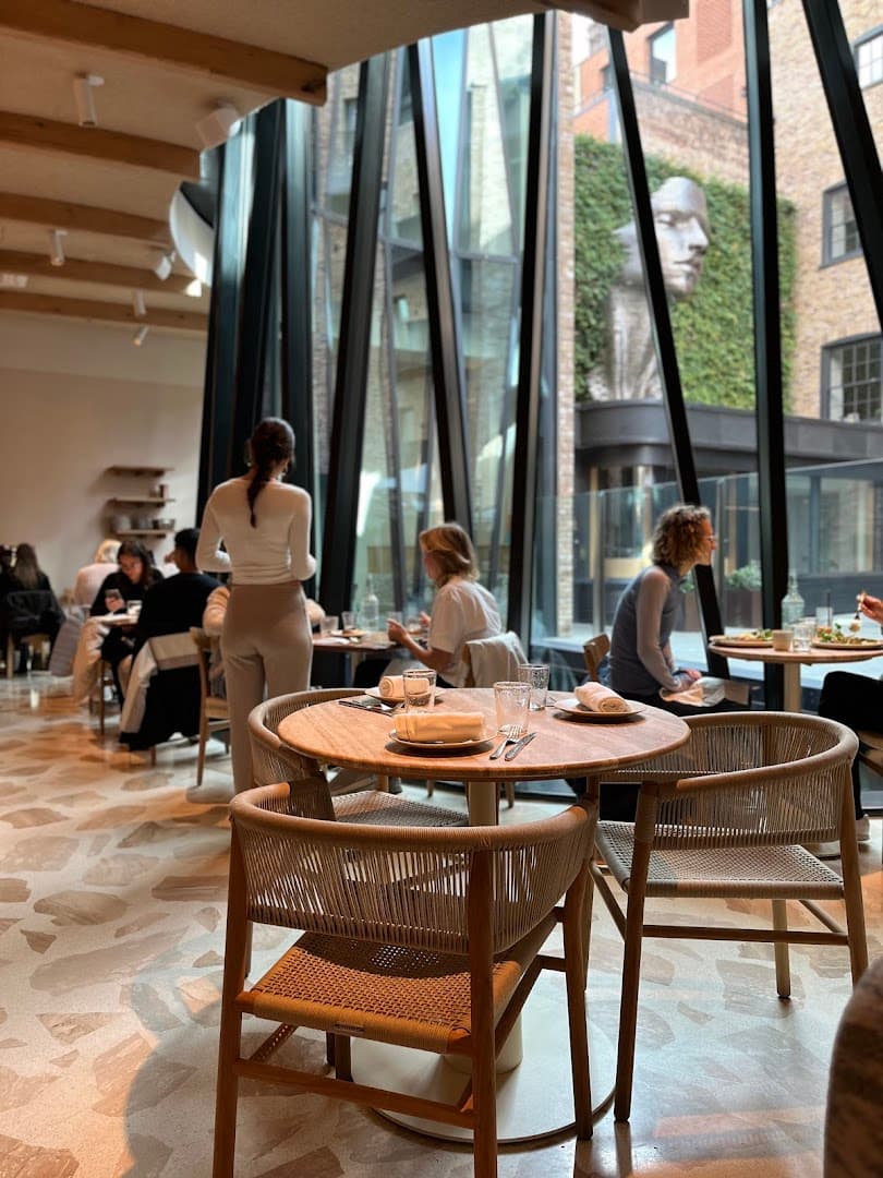 Bright dining room with floor-to-ceiling windows at Milk Beach Soho, London