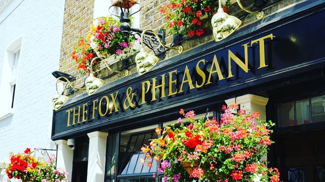 Front facade with colourful hanging baskets at The Fox and Pheasant, London